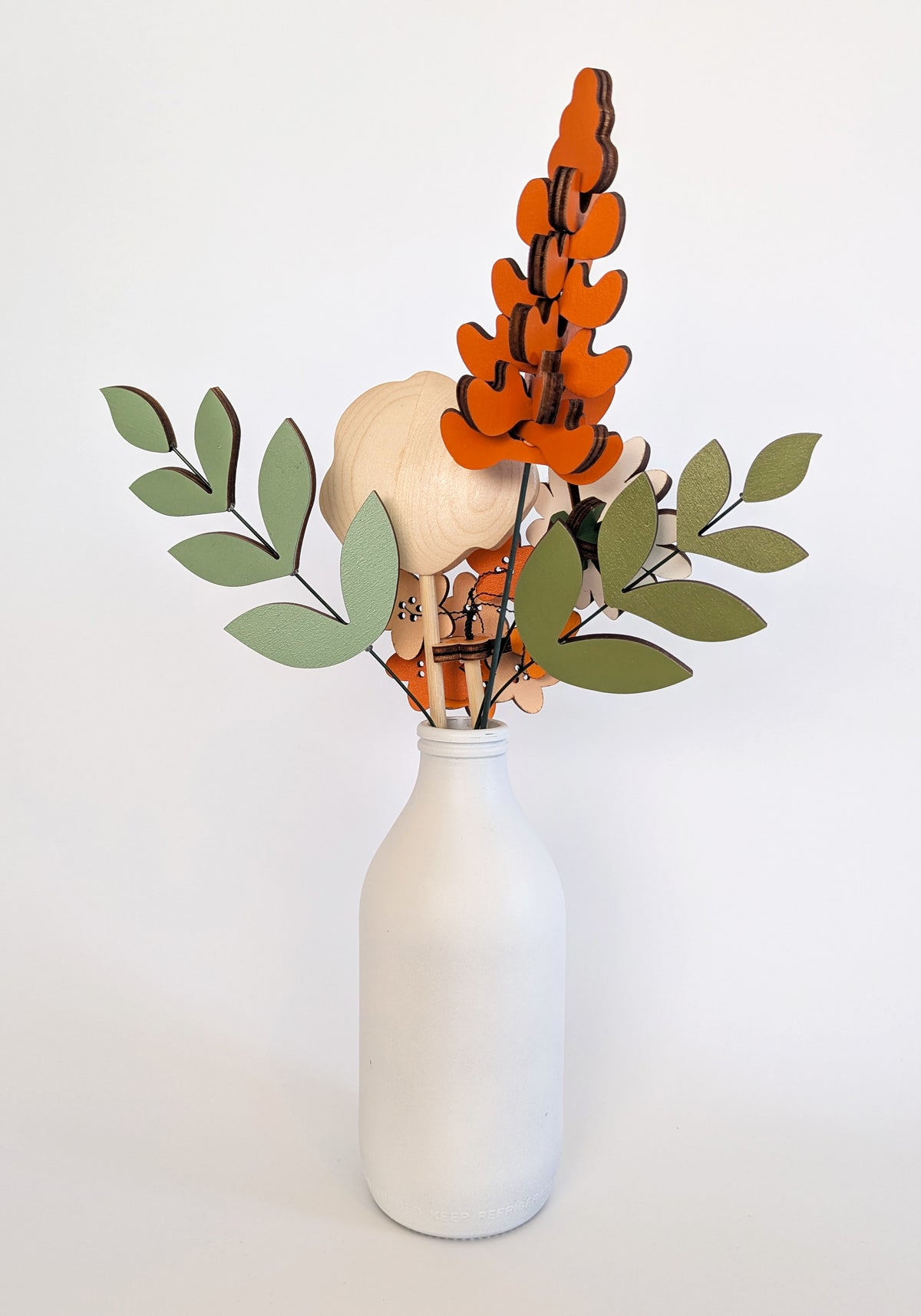 Signature Blooms in Satsuma, four wooden blooms and two foliage stems in warm orange, seen from behind