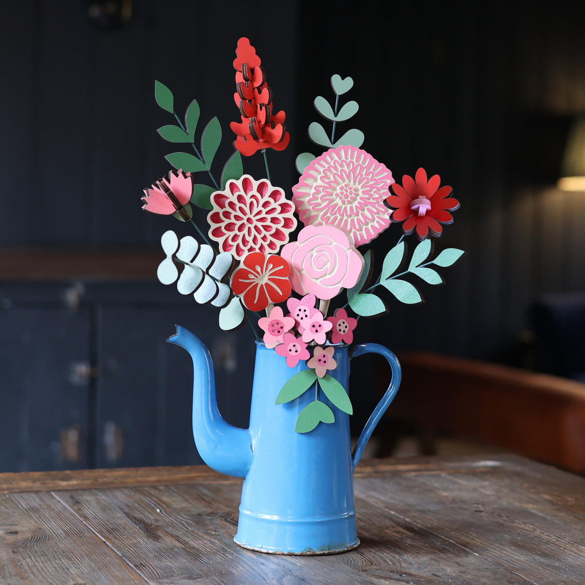 Statement Blooms in Framboise, eight wooden blooms and five foliage sprigs in red, fuchsia and pink, styled in a room 