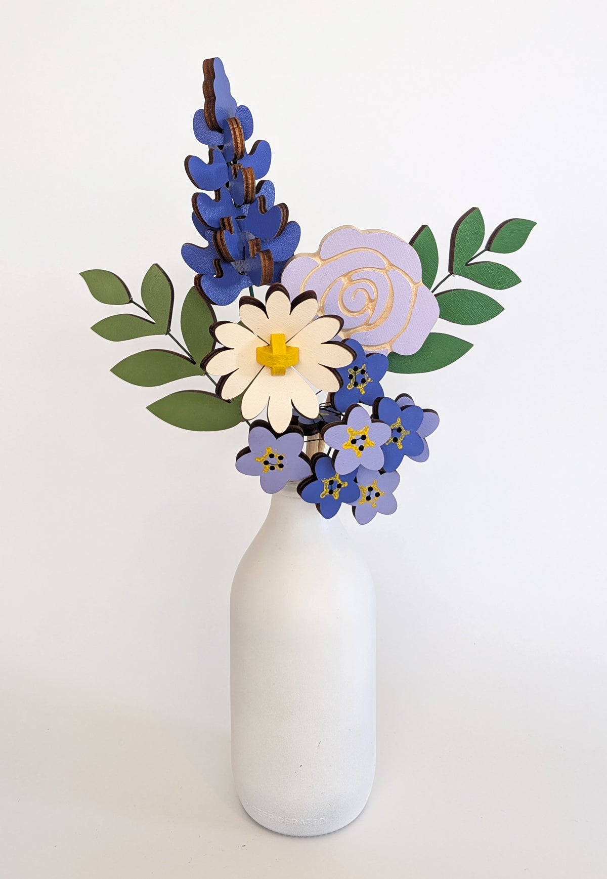 Signature Blooms in Parma Violet, four wooden blooms and two foliage stems in violet and lilac, in a vase 