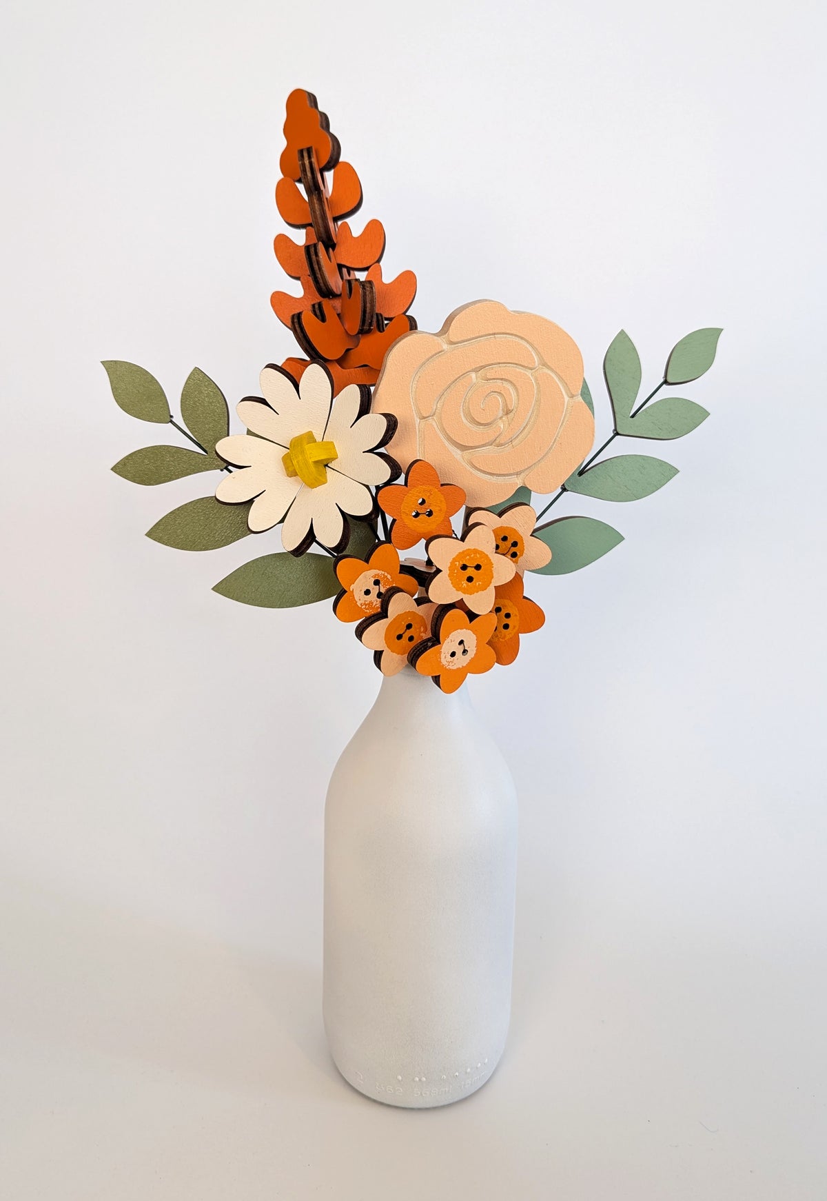 Signature Blooms in Satsuma, four wooden blooms and two foliage stems in warm orange, in a vase 
