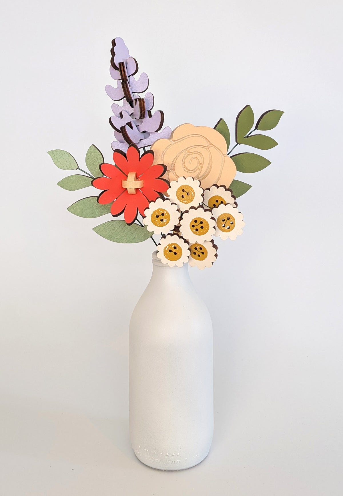 Signature Blooms in Sorbet, four wooden blooms and two foliage stems in muted mustard, lilac, peach, coral and sage, in a vase 